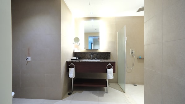 Un baño con lavamanos, espejo, toallero y ducha.