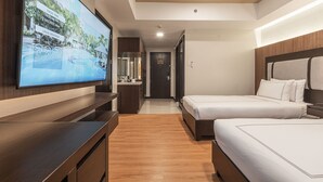 A hotel room with two beds, a TV displaying local weather, and a wooden floor. - Widus Hotel Clark (Mabalacat City)