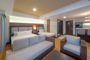 A modern hotel room with a large bed, a smaller bed, a sofa, and a dining area. - Widus Hotel Clark (Mabalacat City)