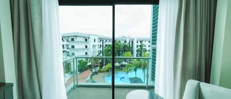 A hotel room with a large sliding glass door leading to a balcony with a pool view.