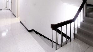 Un interior moderno con una escalera, paredes blancas y un piso de baldosas limpias.