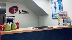 Una recepción de hotel con diseño moderno, que presenta un logotipo, una obra de arte enmarcada y una exhibición de material promocional.