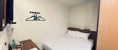 Habitación de hotel con una cama, un escritorio con teléfono, una botella de agua y una bandeja con comida.