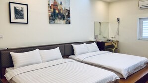 Habitación de hotel con dos camas individuales, un escritorio, una silla, un espejo y dos obras de arte enmarcadas en la pared.