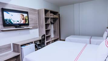 A hotel room with a TV, a desk, a chair, a wardrobe, and two beds.