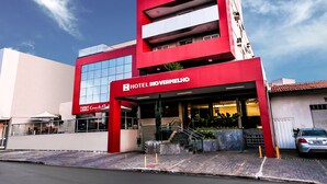 A modern hotel with a red facade, multiple balconies, and a clear sky. - Hotel Rio Vermelho (Goiania)