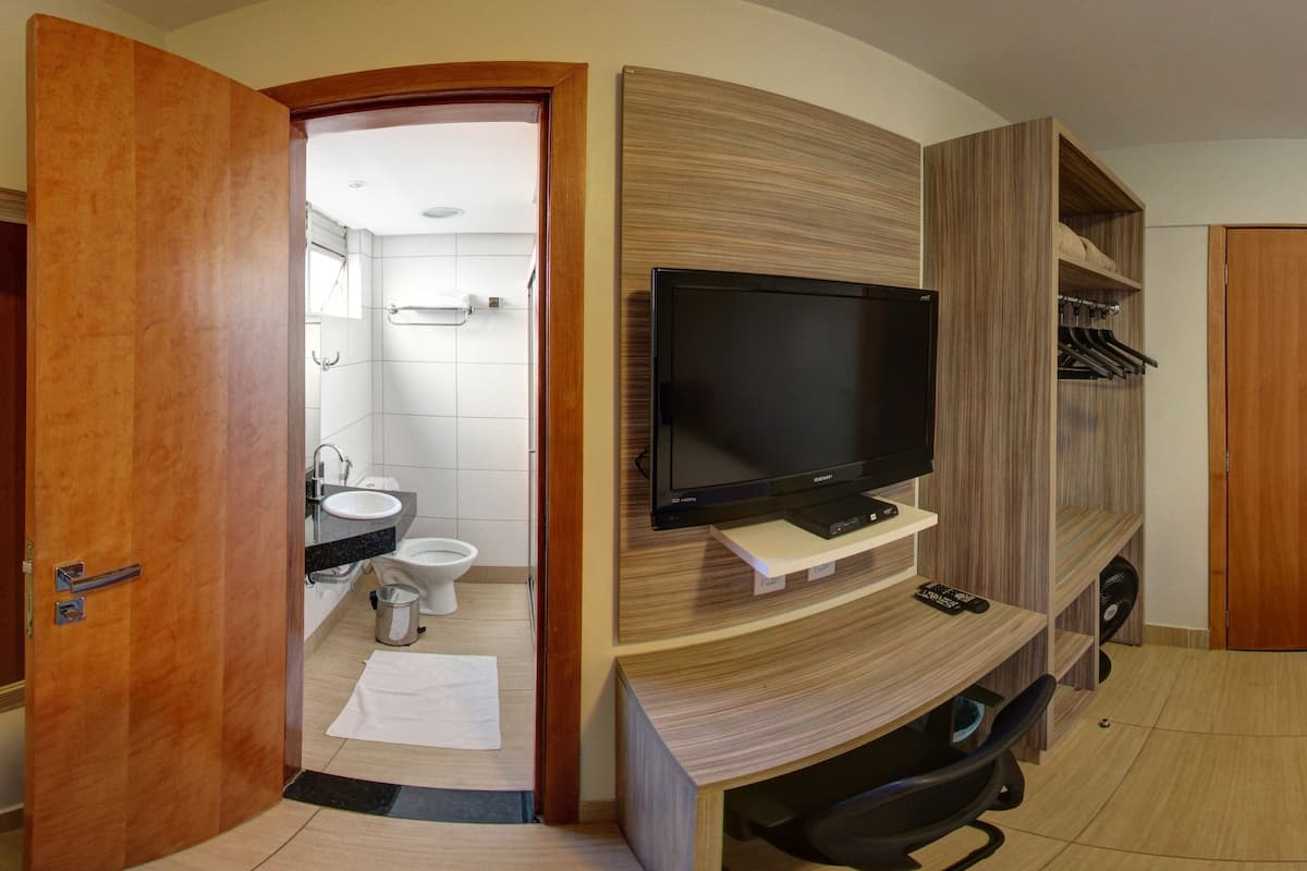 Une chambre d’hôtel équipée d’une télévision, d’un bureau, d’un lit, d’une salle de bain et d’un placard.