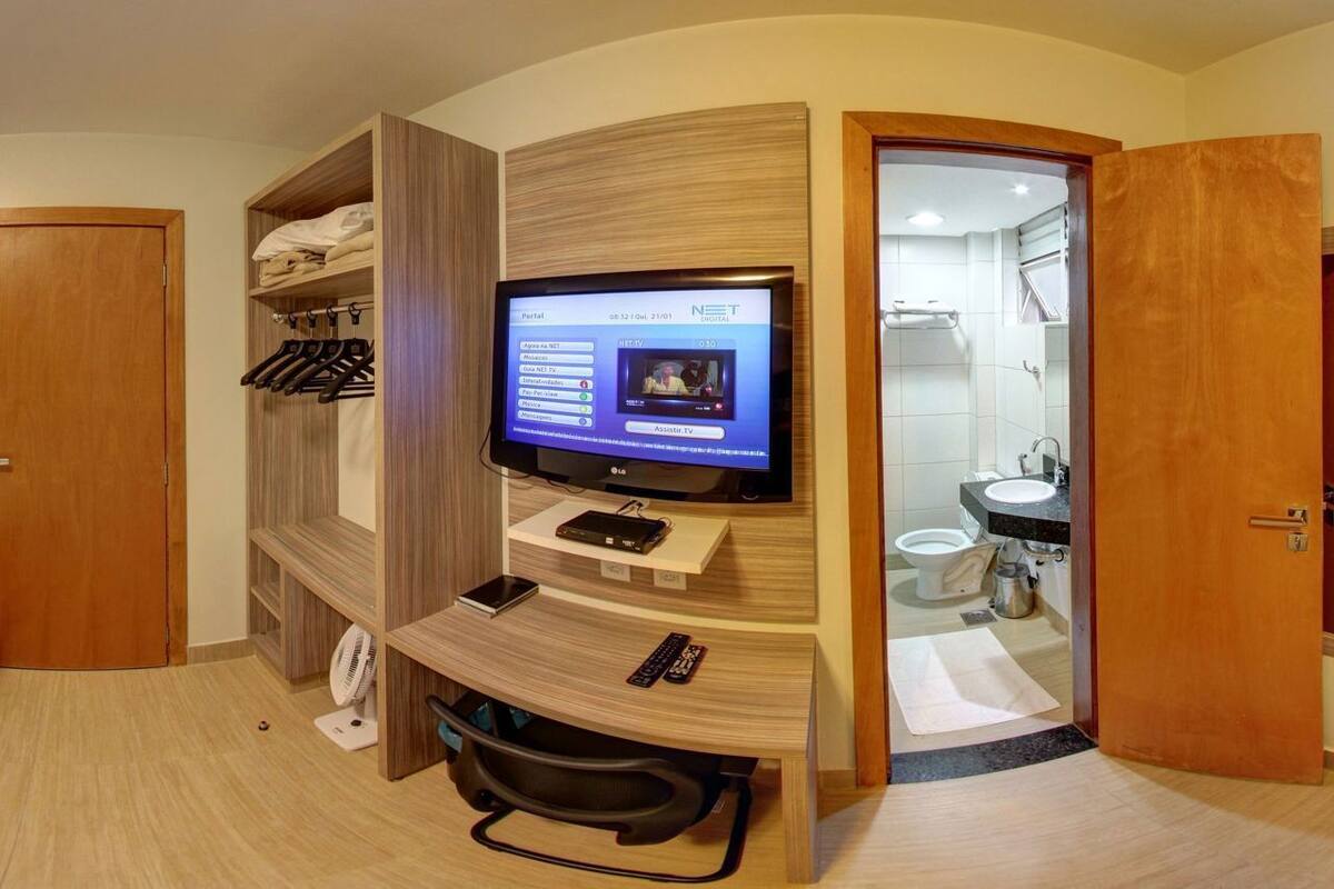 Une chambre d’hôtel avec deux lits simples, une télévision, une armoire et une salle de bain.
