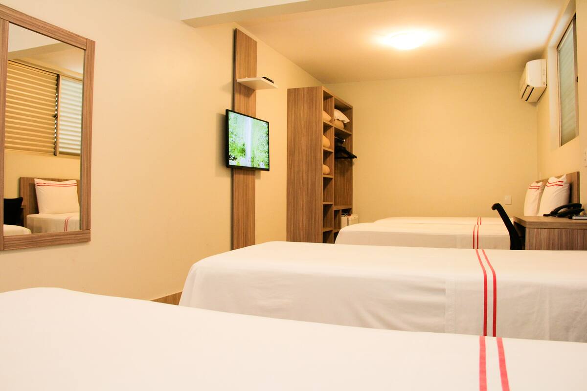 Une chambre d’hôtel avec deux lits, une télévision, un miroir et une armoire.