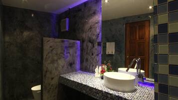 A bathroom with a marble wall, a tiled sink, and a wooden door.