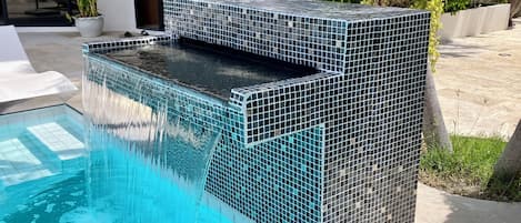A swimming pool with a tiled hot tub area.