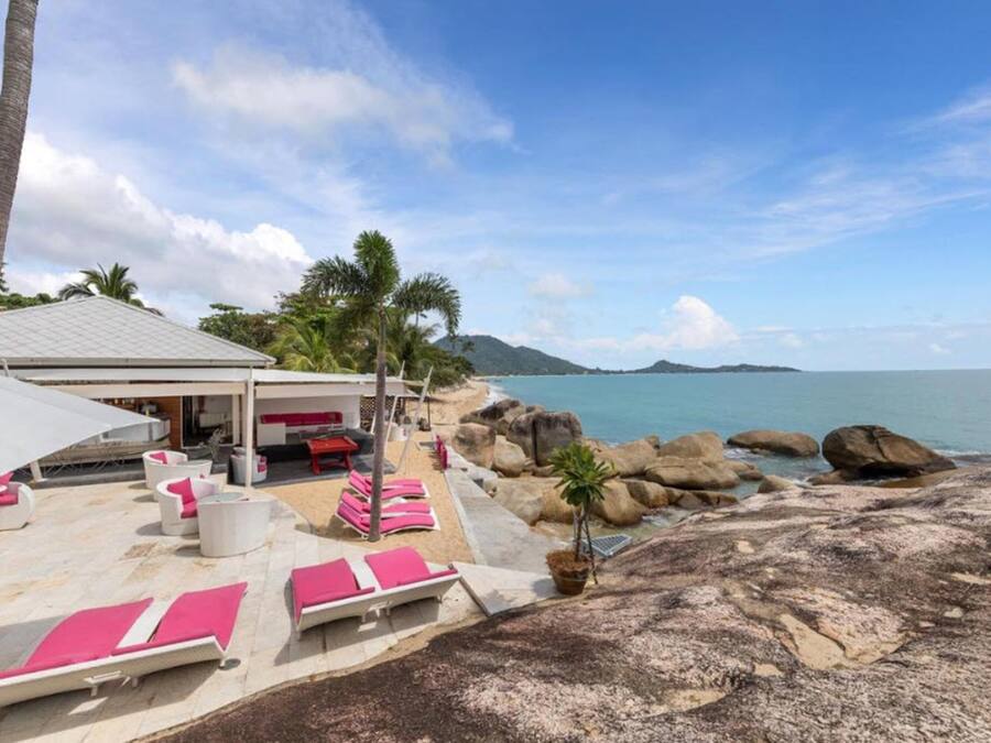 A beachside resort with lounge chairs, a covered seating area, and a view of the ocean.