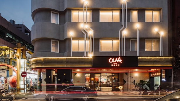 A modern hotel with a curved facade, illuminated windows, and a prominent sign. - OLAH Poshtel - Taichung Station (Taichung)