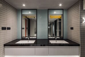 A modern bathroom with two sinks, mirrored walls, and tiled flooring.
