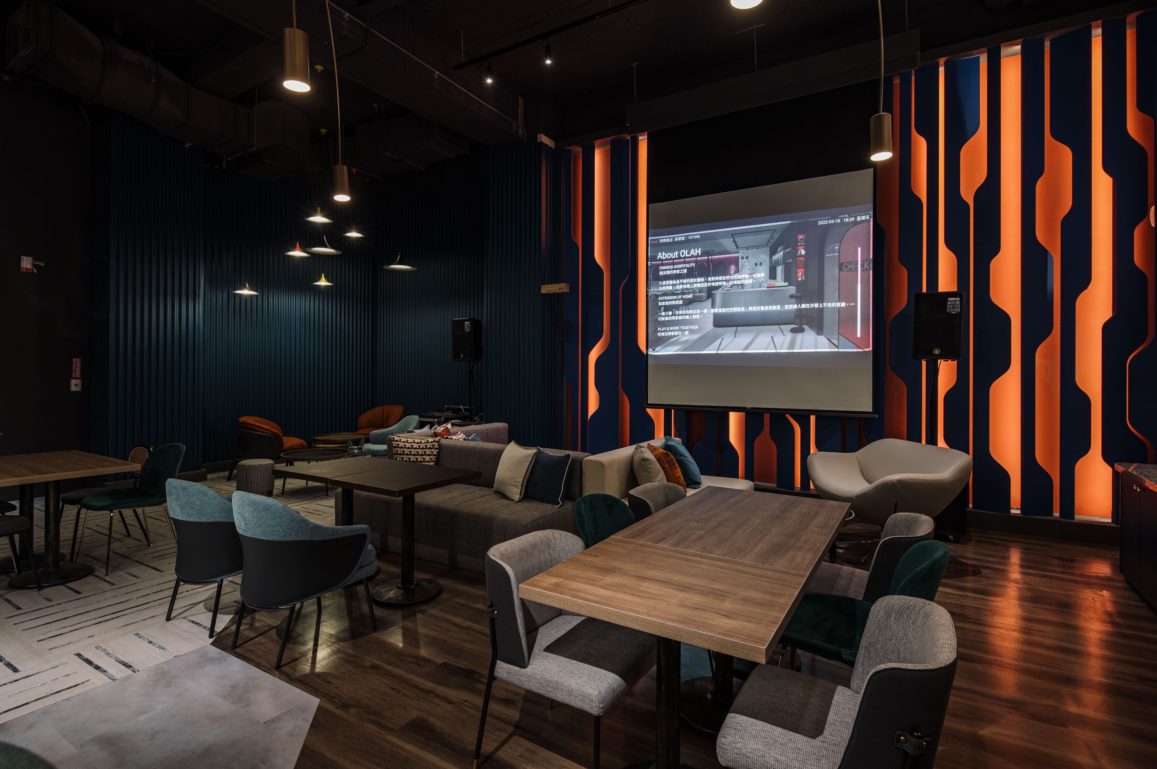 A modern conference room with a large screen, comfortable seating, and a wooden table.
