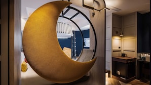 A room with a crescent-shaped hanging chair, a wooden floor, a small table, and a view of a balcony with a railing. - OLAH Poshtel - Taichung Station (Taichung)