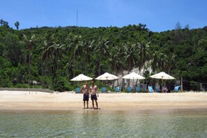 A beach with clear water, umbrellas, and chairs.