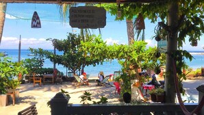 En café ved stranden med udendørs siddepladser, et træbord og havudsigt.