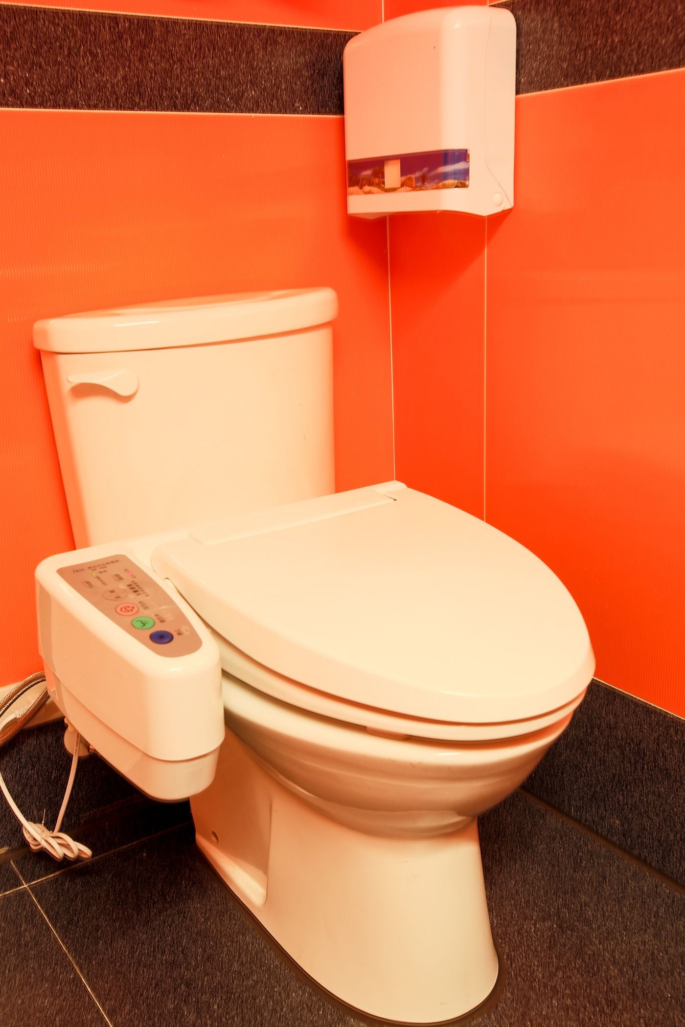 Des toilettes modernes dotées d’un panneau de commande et d’un distributeur de gel hydroalcoolique fixé au mur.