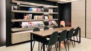 A modern library with bookshelves, a wooden table, and chairs. - HUB Hotel Tucheng (New Taipei City)