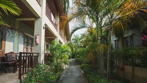 A narrow pathway flanked by lush greenery and a building with balconies. - Buathong Place (Koh Samui)