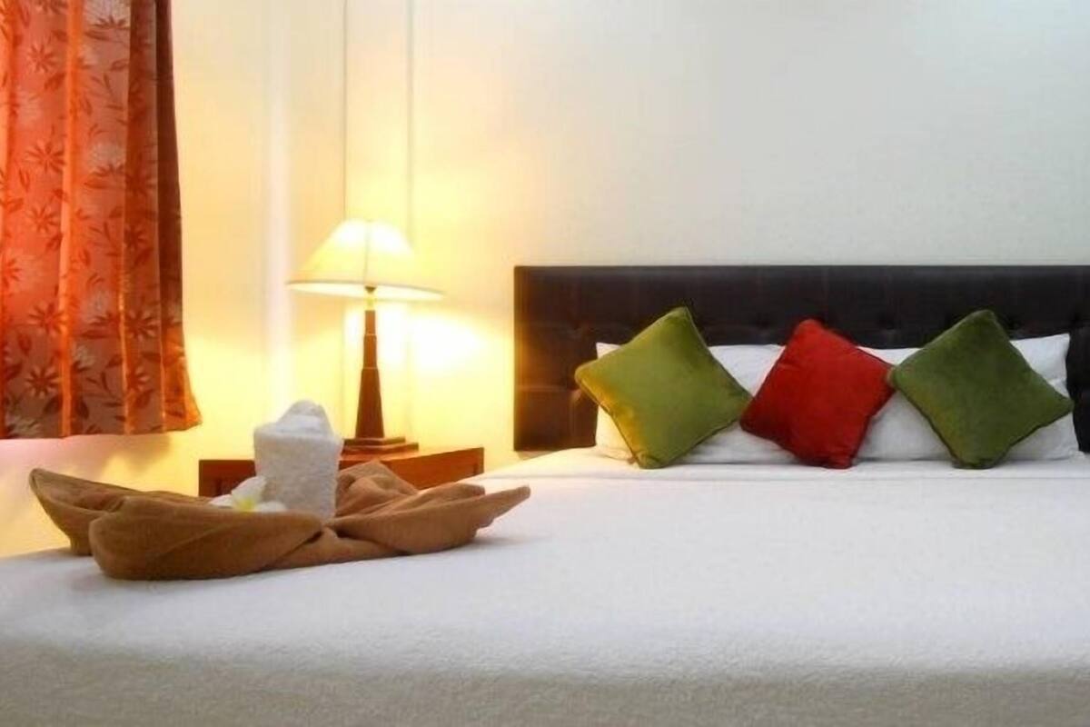 A neatly made bed with a headboard, pillows, and towels arranged on either side.