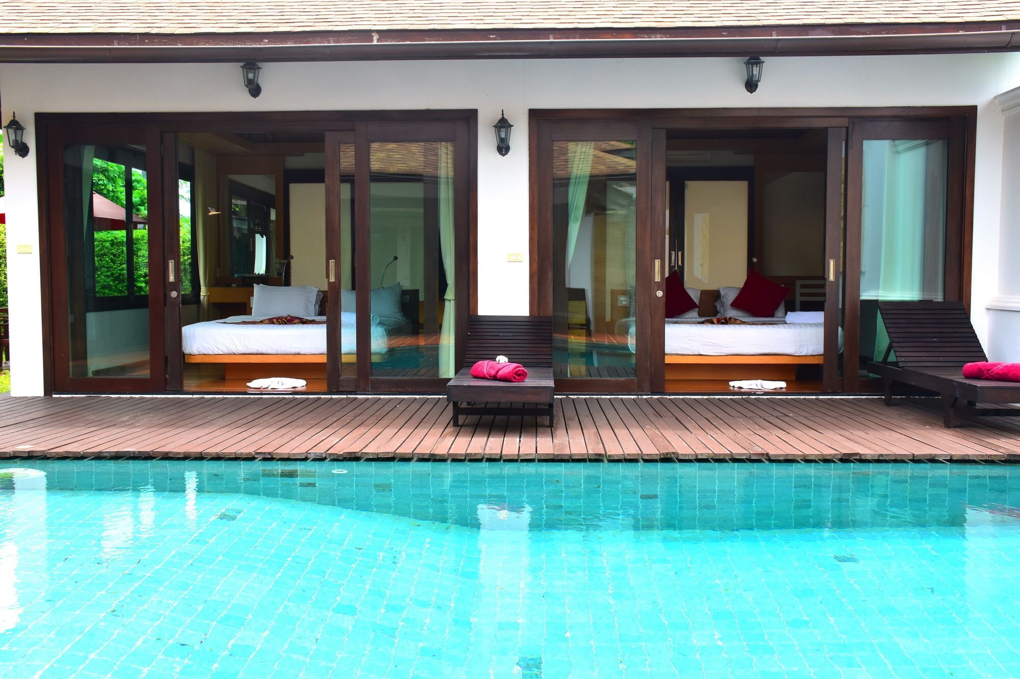 A hotel with a pool, two bedrooms with beds, and a bench.