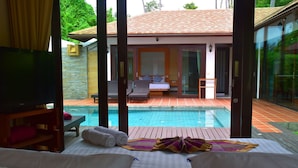 Quarto de hotel com cama, piscina e vista para a área da piscina.