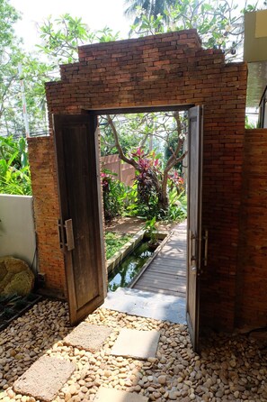 Entrada de maó a una zona de jardí amb una petita font i pedres.