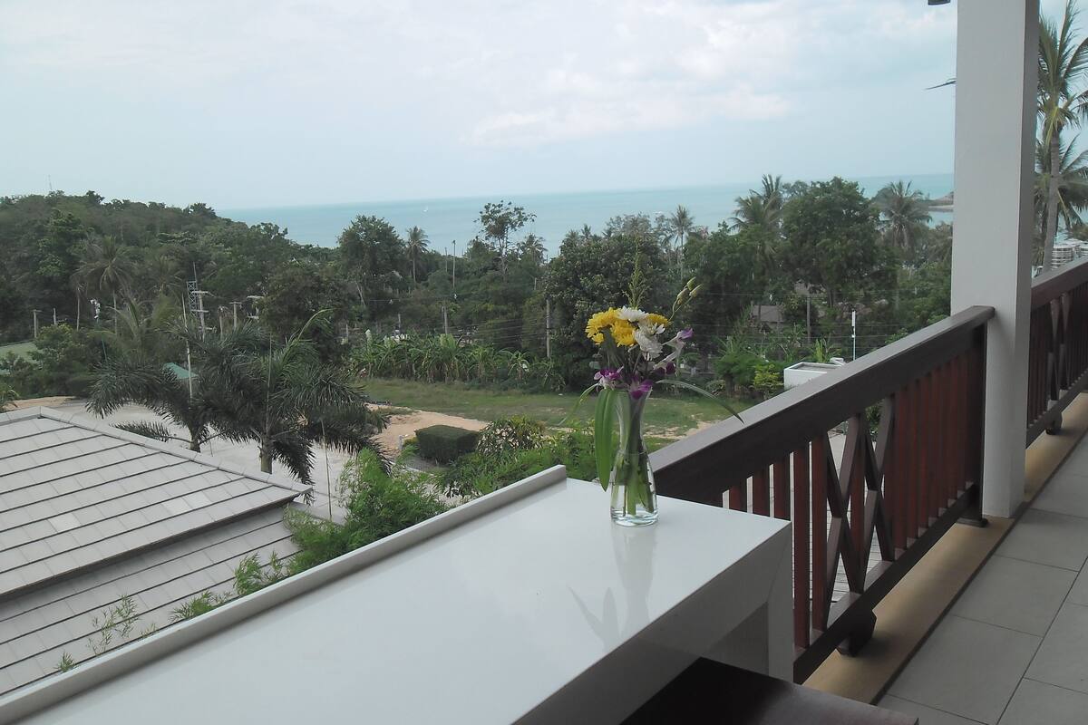 A balcony with a clear view of the ocean and lush greenery.