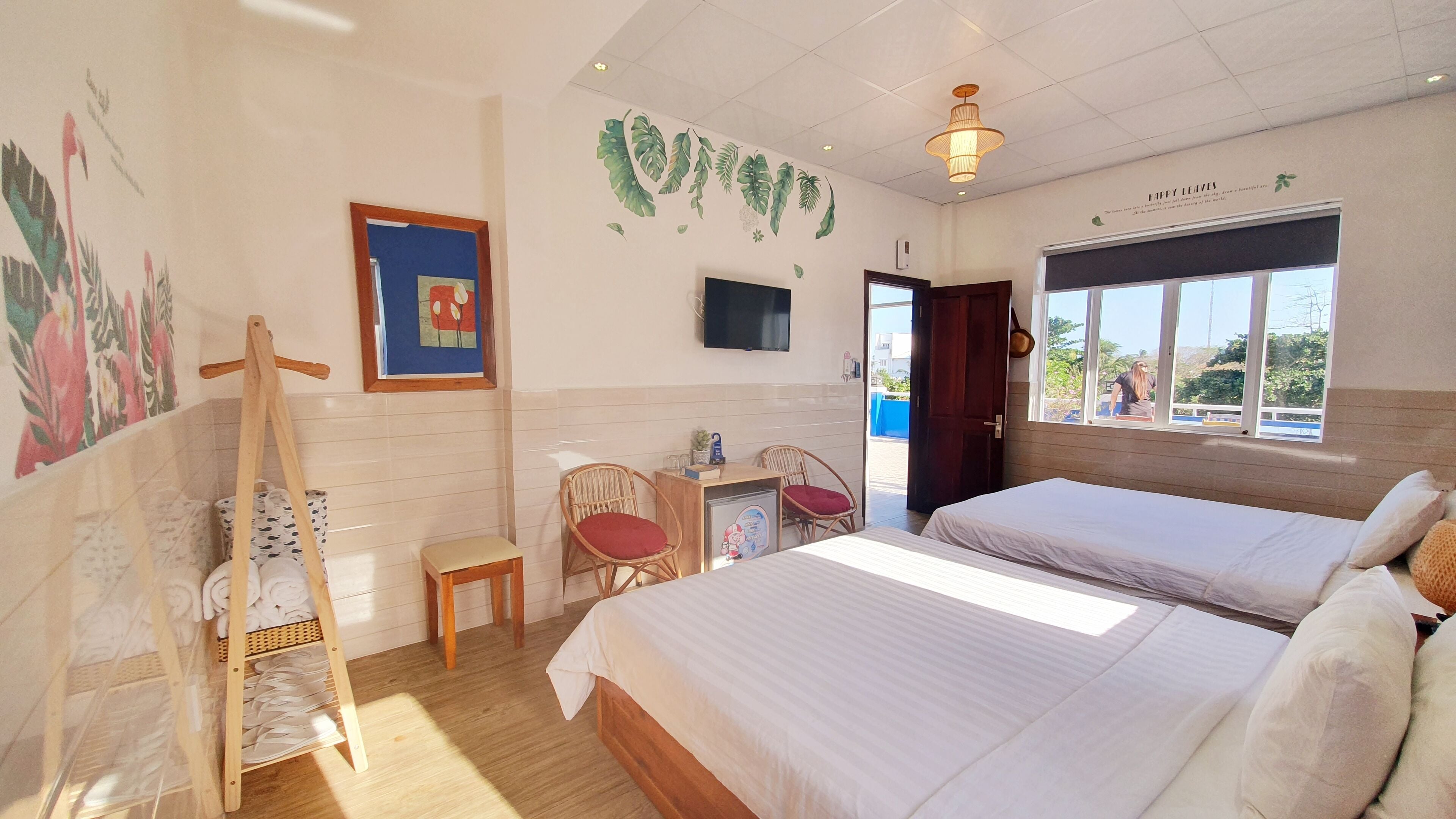 Habitación de hotel con dos camas, un escritorio con silla, televisión y ventana con vistas.