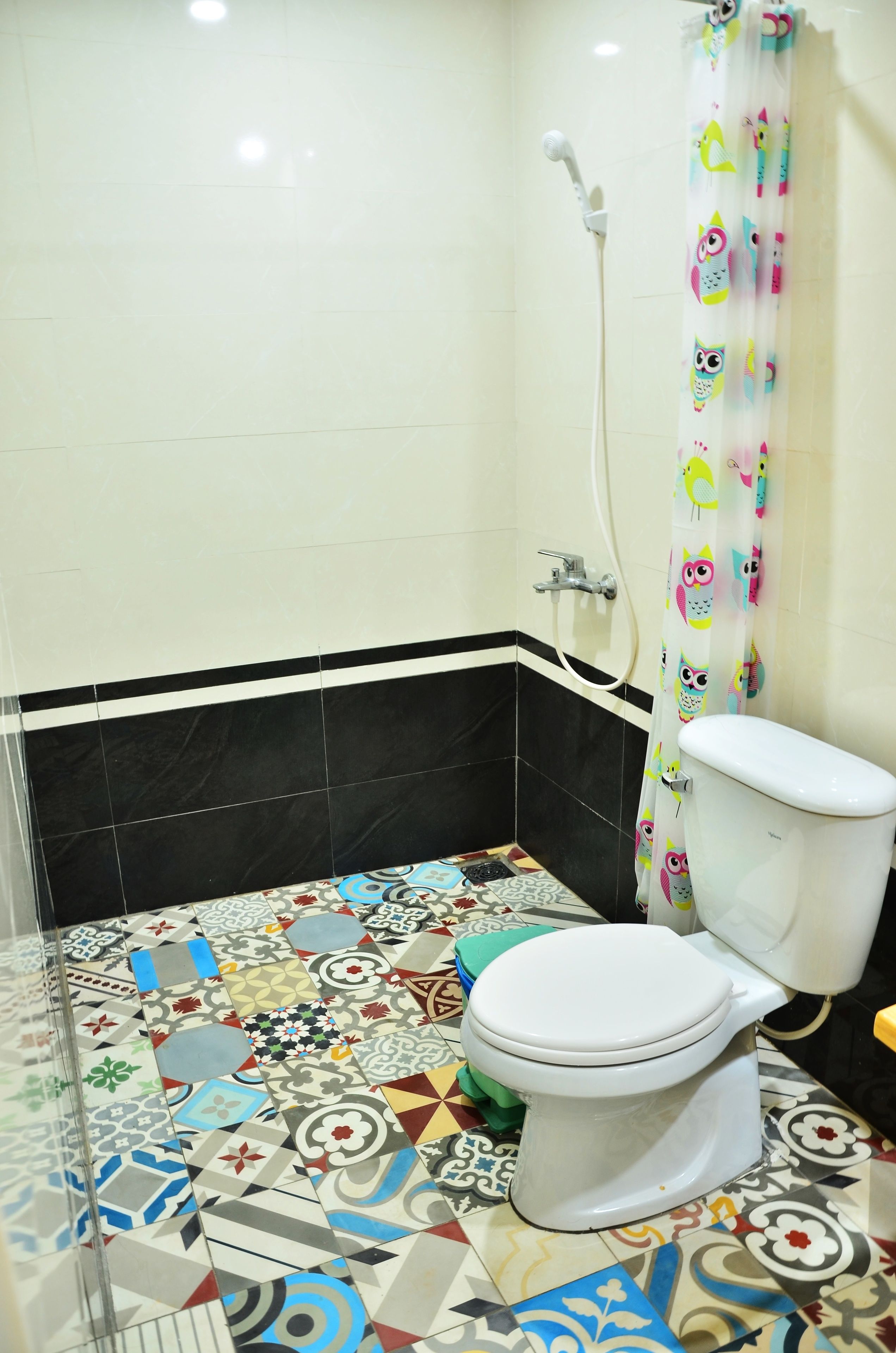 Ein Badezimmer mit Toilette, Dusche und einem farbenfrohen Fliesenboden.