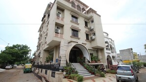 Un edificio de varios pisos con una entrada central, balcones y una escalera que conduce a la entrada.