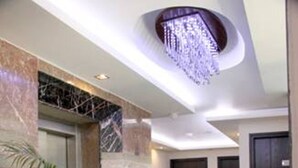 Un vestíbulo de hotel moderno con paredes de mármol, piso estampado y una araña.