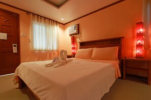 Une chambre d’hôtel avec un lit, une table de chevet, un climatiseur fixé au mur et une fenêtre avec des rideaux.