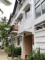 Un edificio de varios pisos con balcones, unidades de aire acondicionado y un cartel.