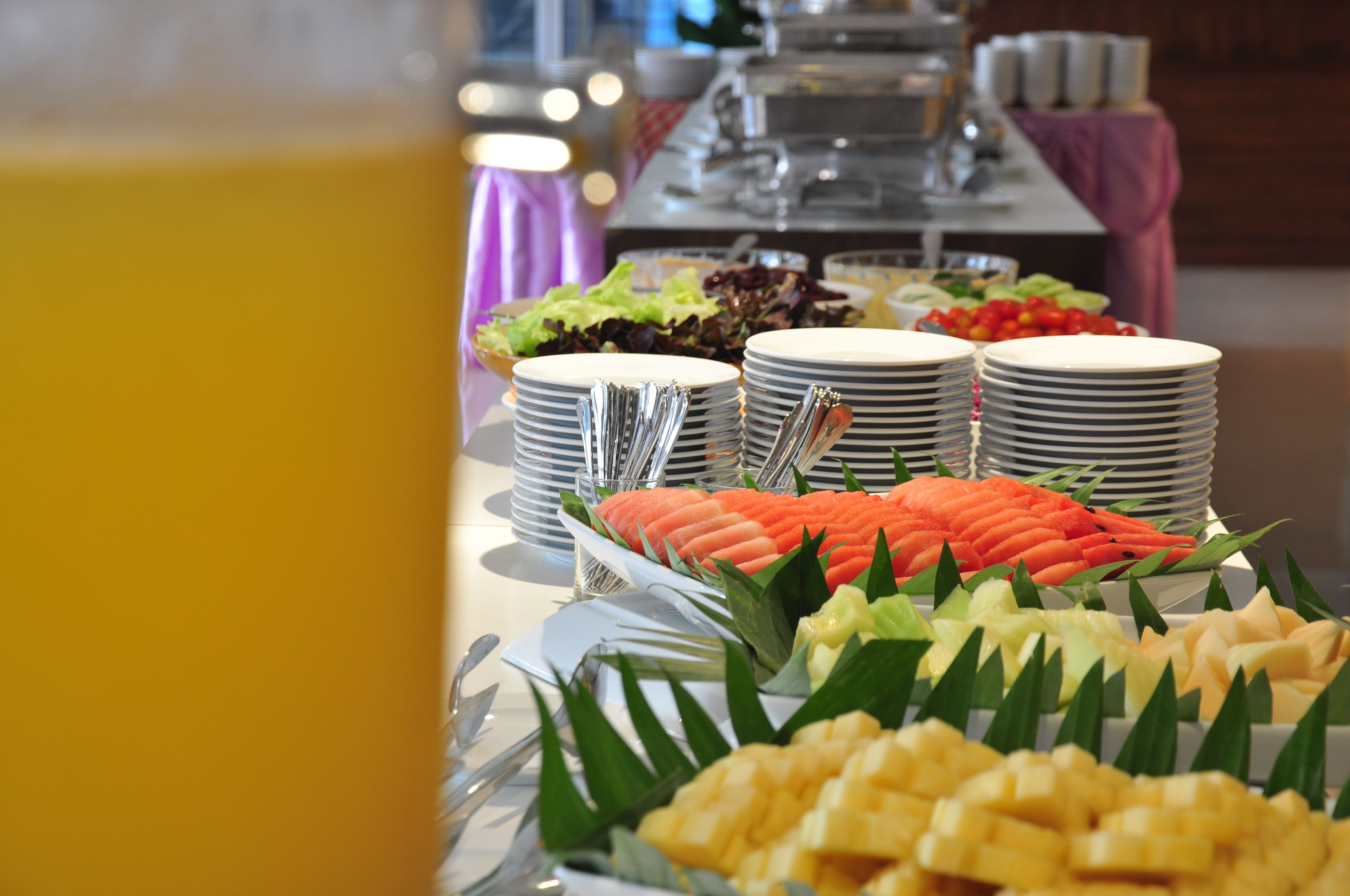 A buffet table with various food items and stacked plates.