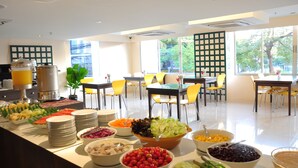 A buffet area with various food items and a seating arrangement with yellow chairs. - Mayflower Grande Hotel Chiang Mai (Chiang Mai)