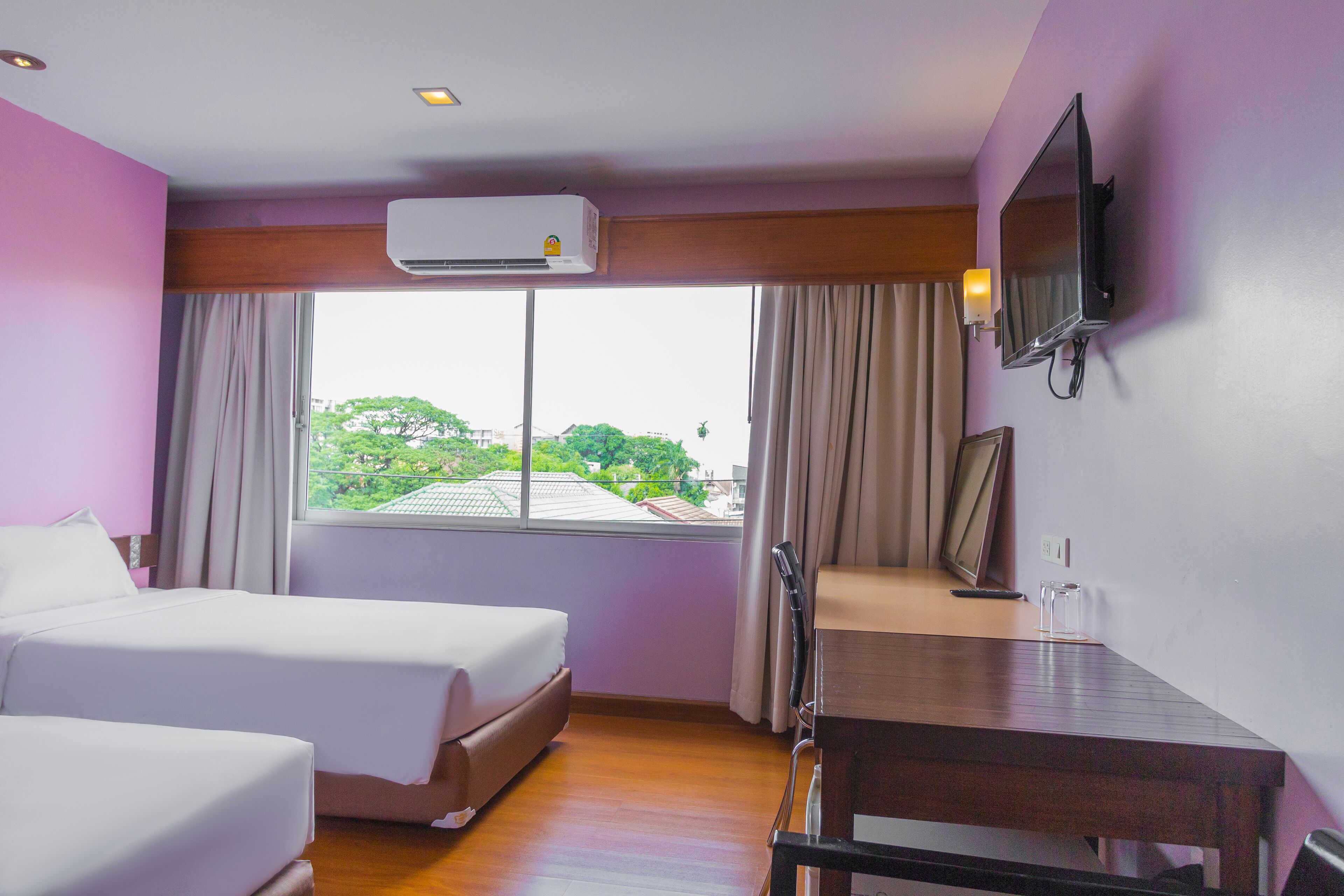 Habitación de hotel con dos camas, un escritorio, un televisor y un aire acondicionado.