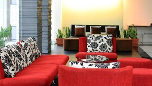A modern lobby with red sofas and patterned cushions, a stone accent wall, and potted plants. - Mayflower Grande Hotel Chiang Mai (Chiang Mai)