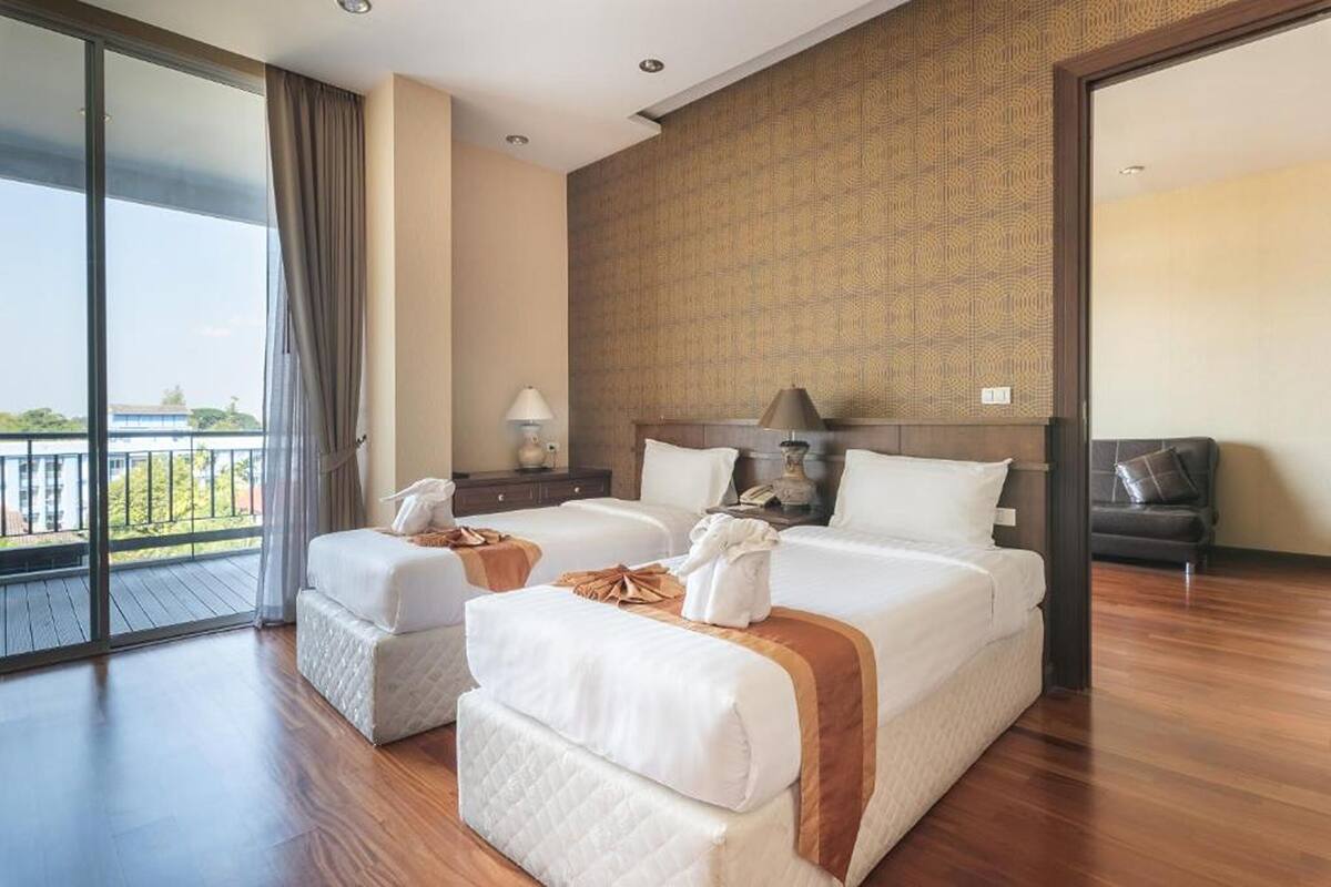 Een hotelkamer met twee bedden, een balkon, een bureau en een stoel.