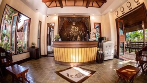 Un área de recepción con un mostrador de madera, un candelabro y un amplio panel decorativo.