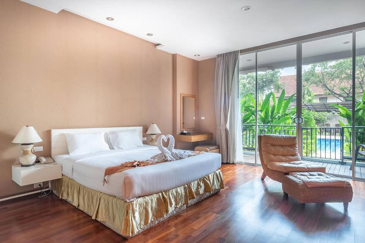 Een hotelkamer met een groot bed, een zithoek met een fauteuil, een nachtkastje en uitzicht op het omliggende landschap.