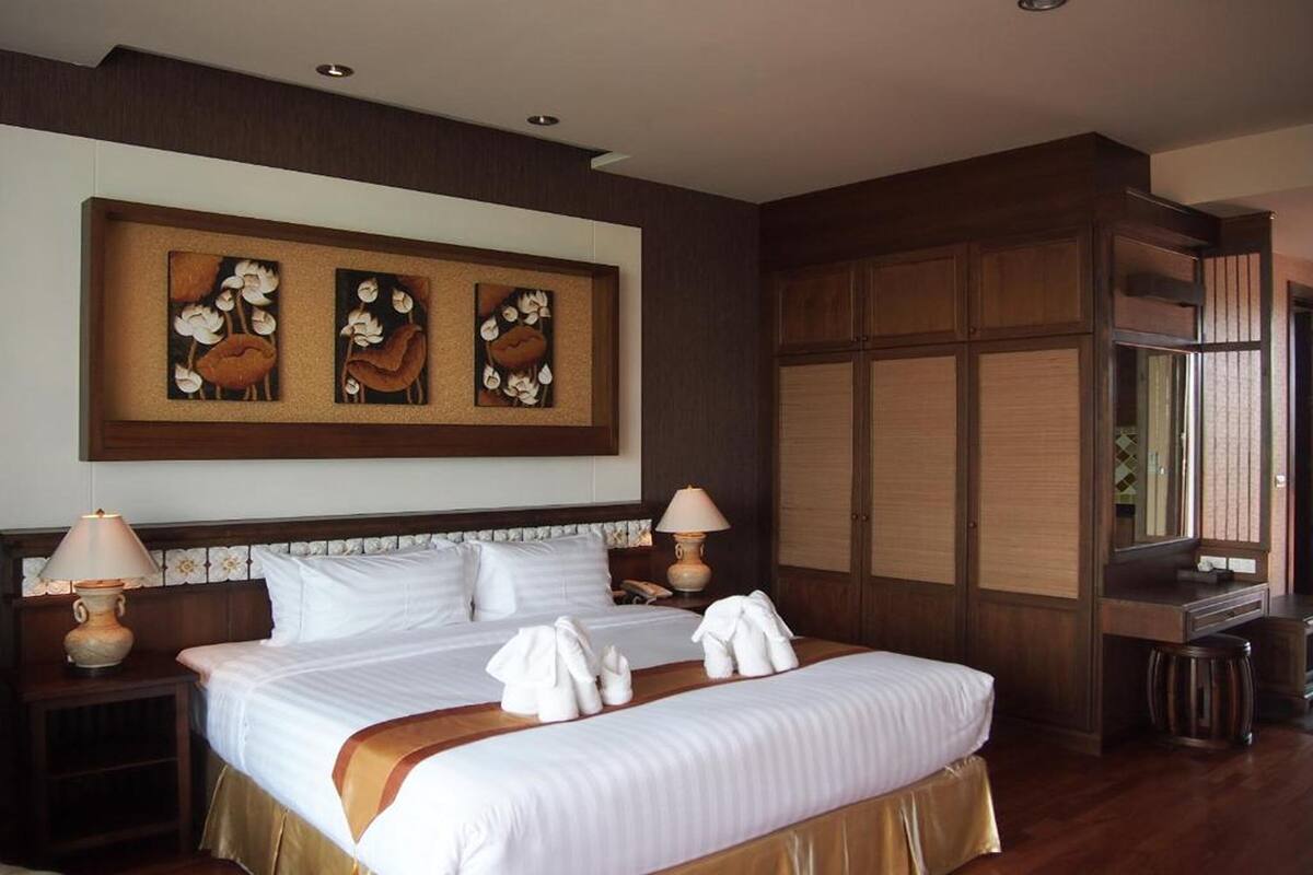 Een hotelkamer met een groot bed, twee bedlampen, een houten hoofdeinde en een wanddecoratie.