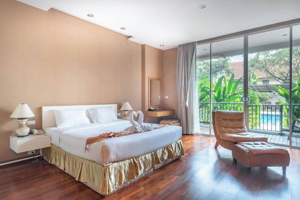 Een hotelkamer met een bed, nachtkastjes, een stoel en een balkon met uitzicht.