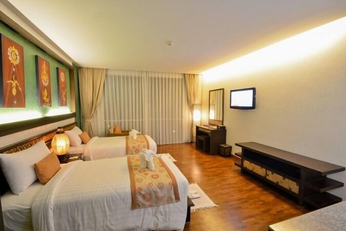 A hotel room with two beds, a TV, a desk, and a console table.