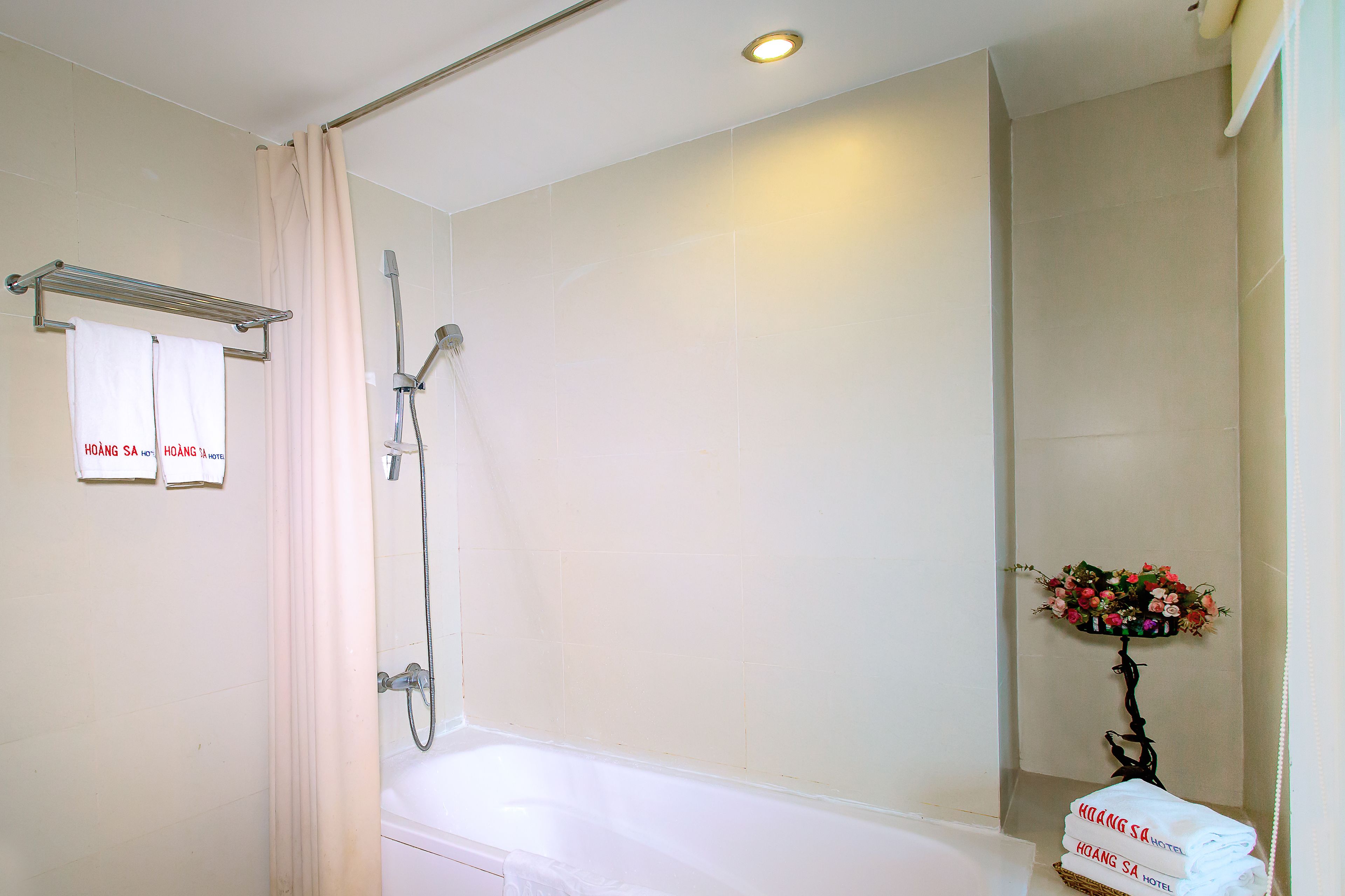A bathroom with a bathtub, a shower, and a towel rack with towels.
