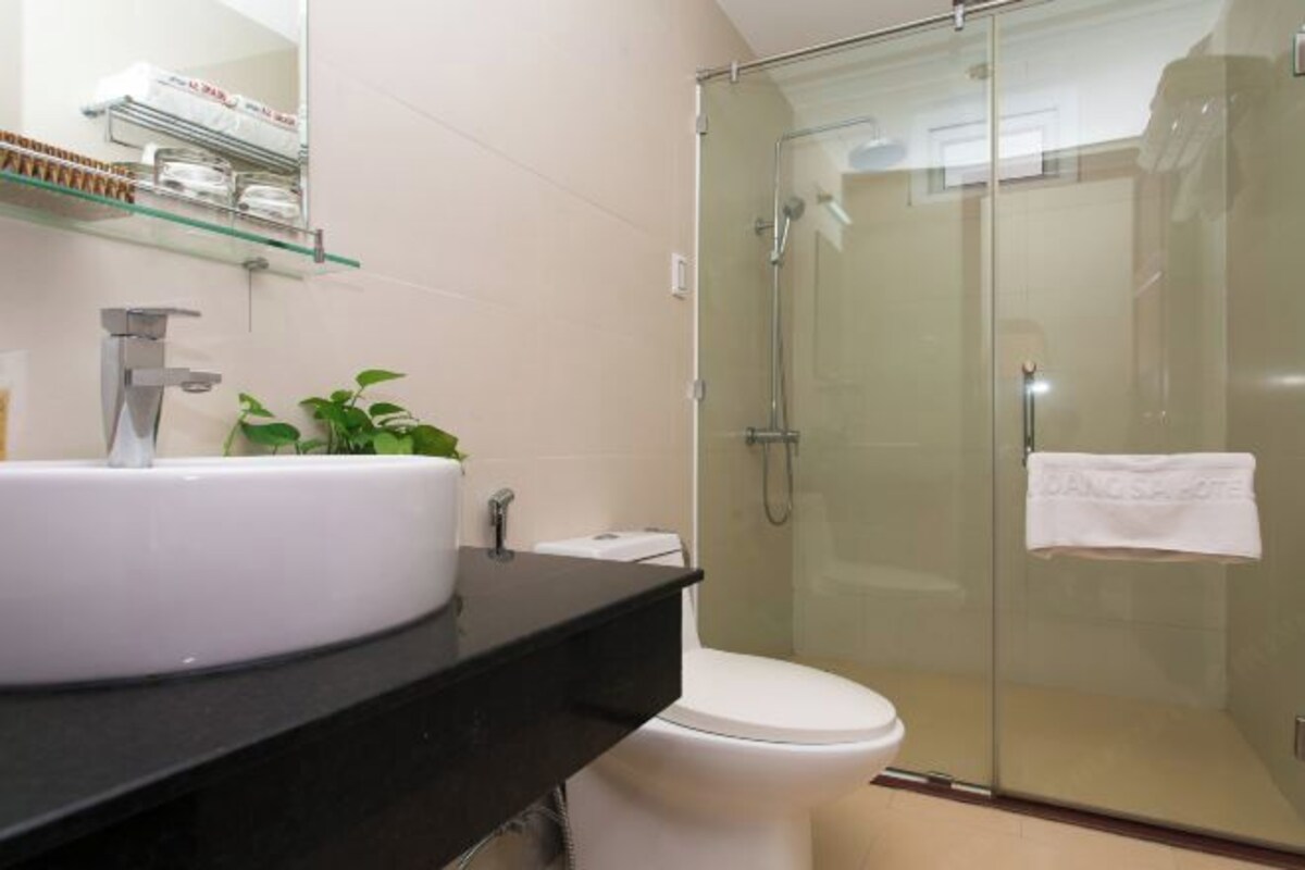 A bathroom with a glass-enclosed shower, a white sink, and a toilet.