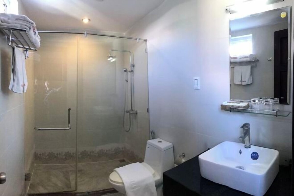 A bathroom with a glass-enclosed shower, a white sink, and a mirror above the sink.