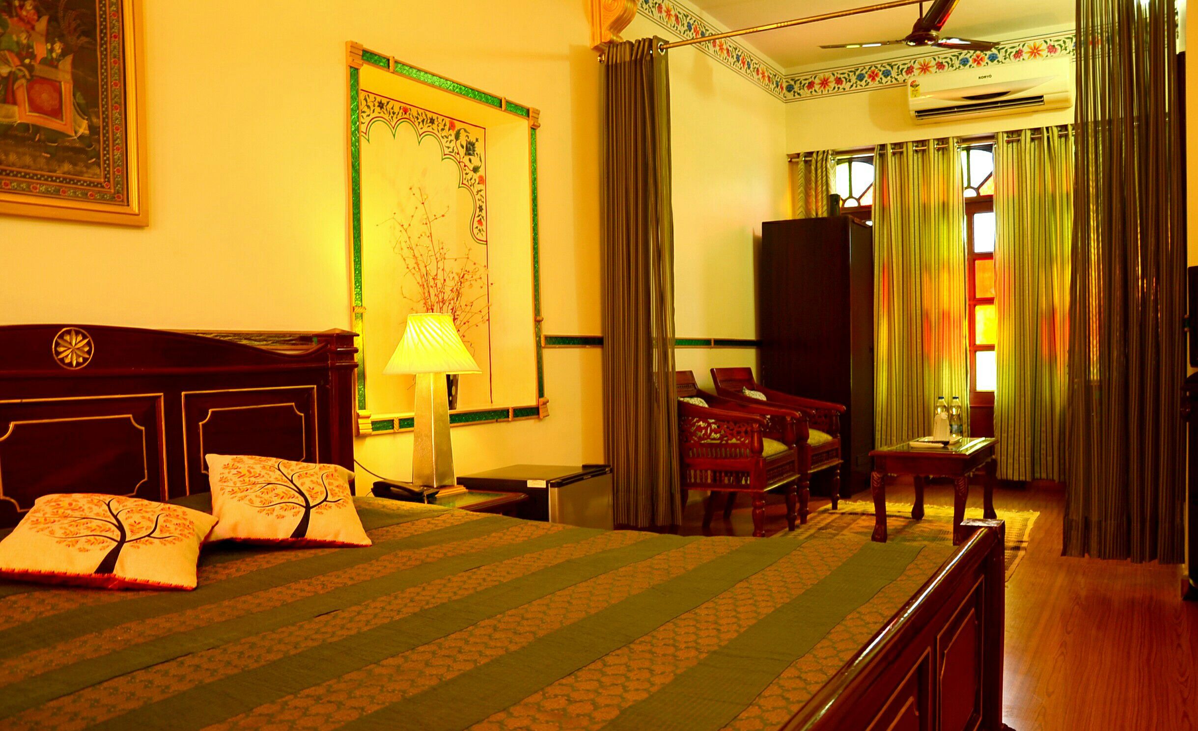 A hotel room with a bed, a desk, a chair, a TV, and curtains.